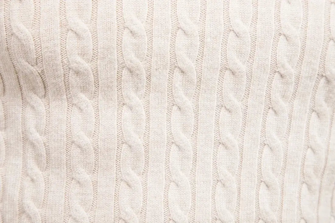 Cream-colored men’s cable knit turtleneck pullover sweater featuring a textured interwoven pattern.