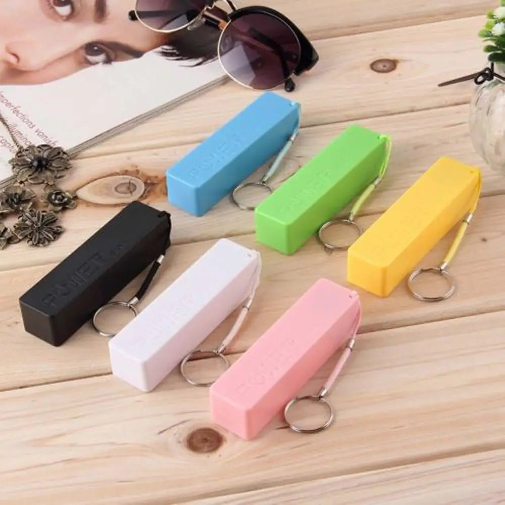A set of colorful portable power banks for 18650 battery with micro usb and keychain loop in blue green yellow pink white and black.