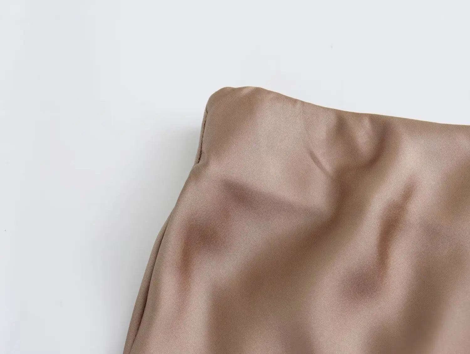 Une jupe midi en satin taupe tendre, à taille haute, avec un tissu lisse légèrement réfléchissant pour un look de longue jupe élégante