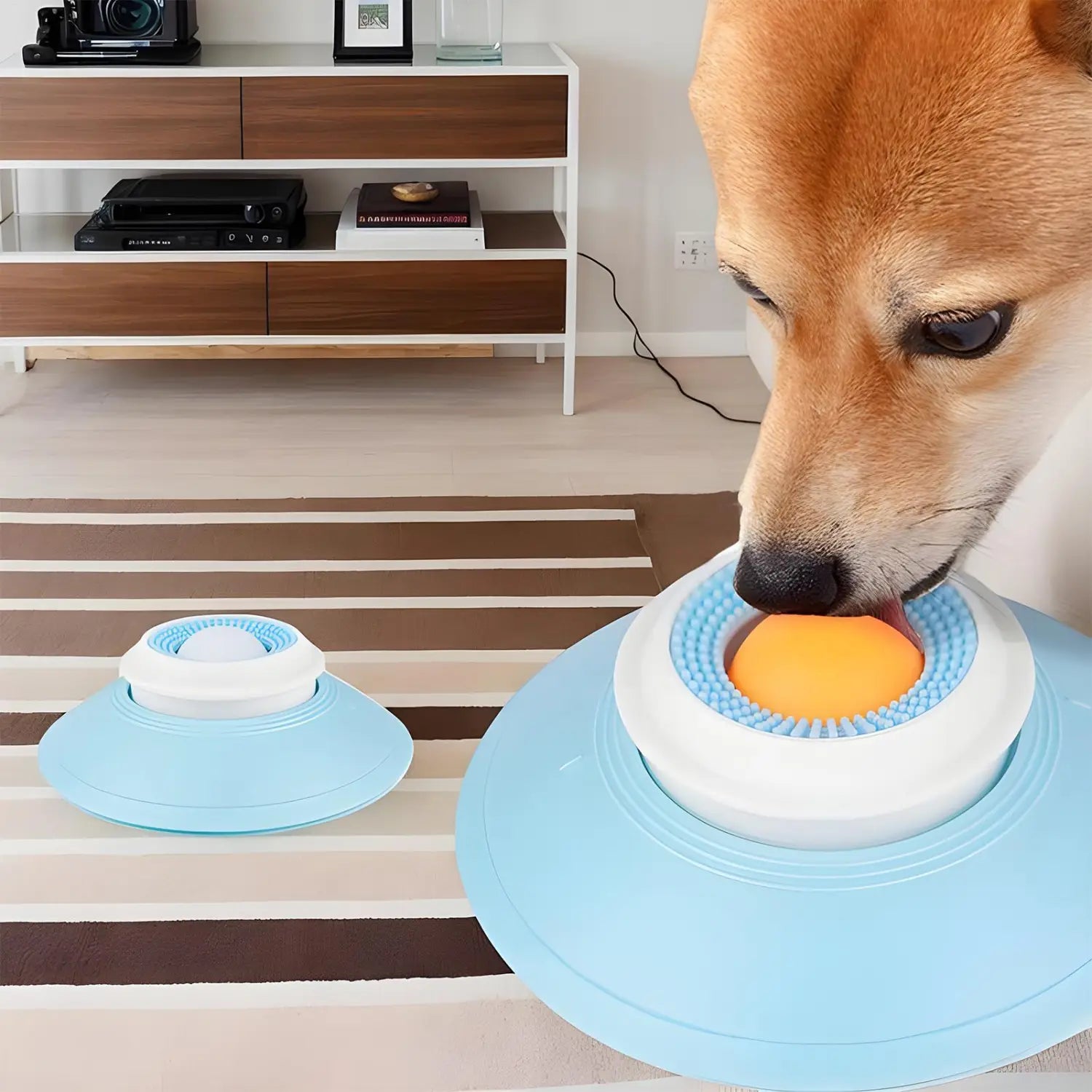 明るい青色と白色のプラスチック製の犬用リックトイで、質感のある表面と内側にオレンジ色のボールを備えた、インタラクティブなスローフィーダーボールとして設計されています。
