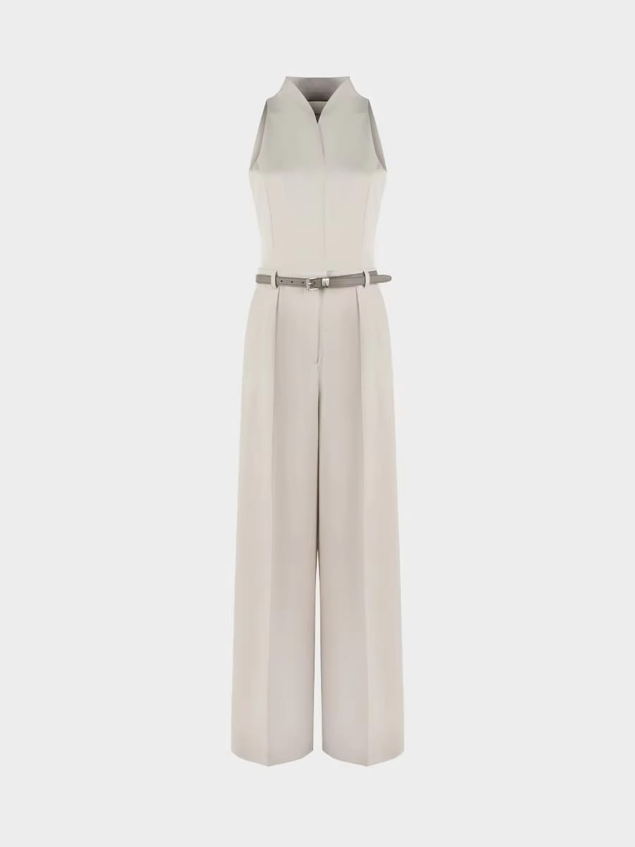 Une combinaison beige sans manches élégante, avec un col tailleur, un pantalon à jambes larges et une ceinture assortie.