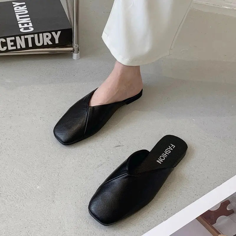 Schwarze Maultier-Slipper aus Leder mit quadratischer Zehenpartie mit einem eleganten, minimalistischen Design und einer glatten Oberfläche für stilvolle flache Slipper.