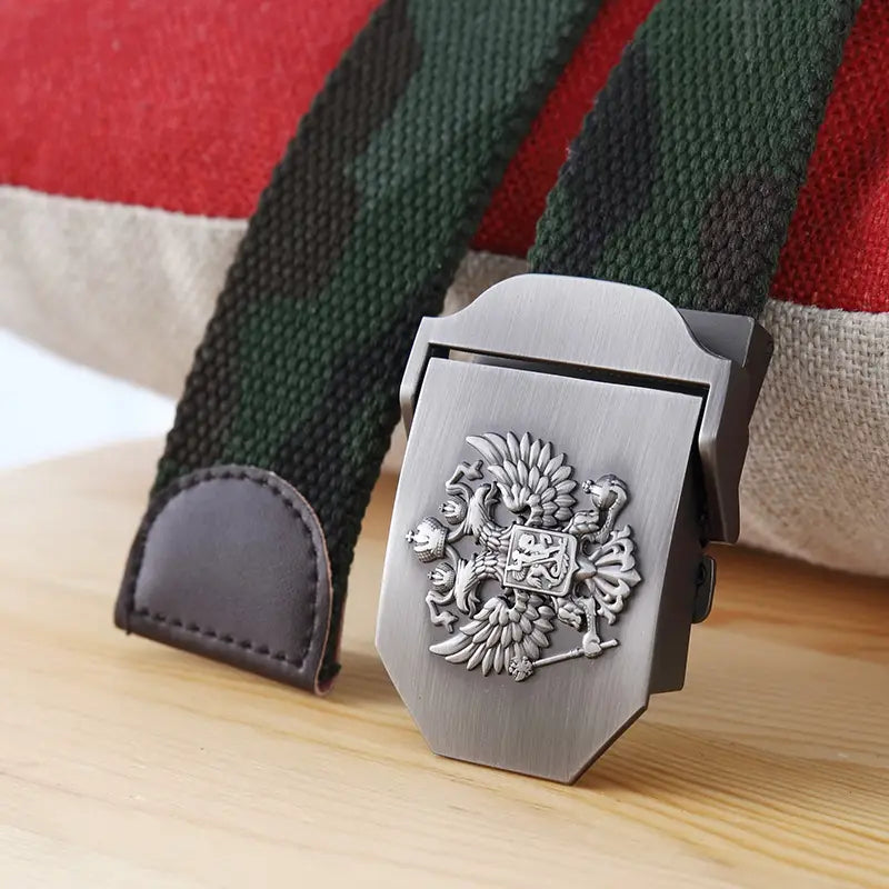 Boucle de ceinture à finition ton argent avec un emblème d’aigle bicéphale en relief, sangle en toile camouflage vert, et extrémité en cuir brun foncé sur une ceinture tactique en toile à aigle russe pour hommes, pour un usage militaire.
