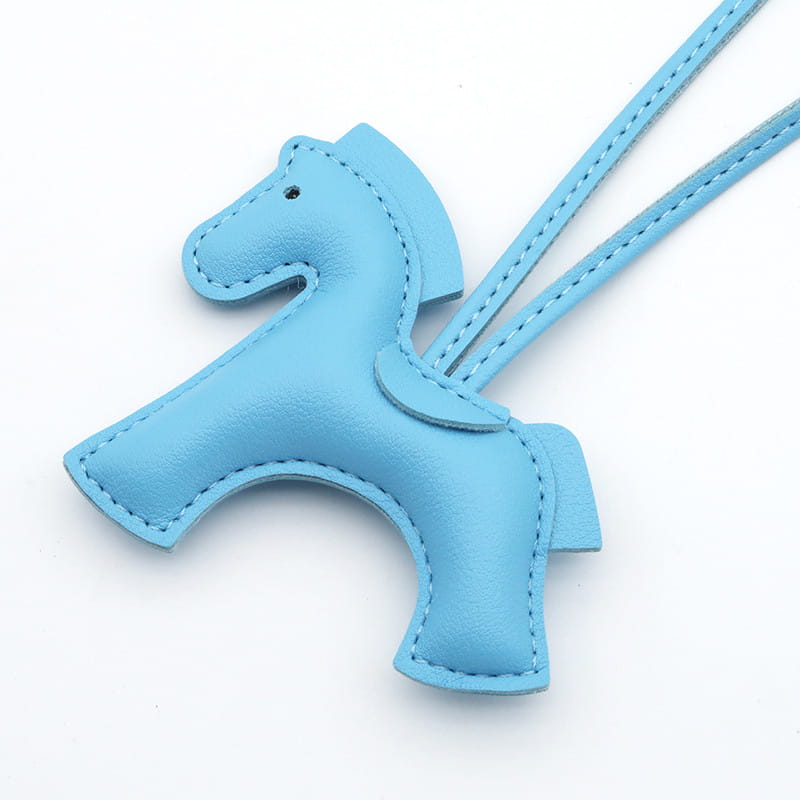 Porte-clés en cuir bleu clair en forme de cheval avec détails cousus et lanière assortie.