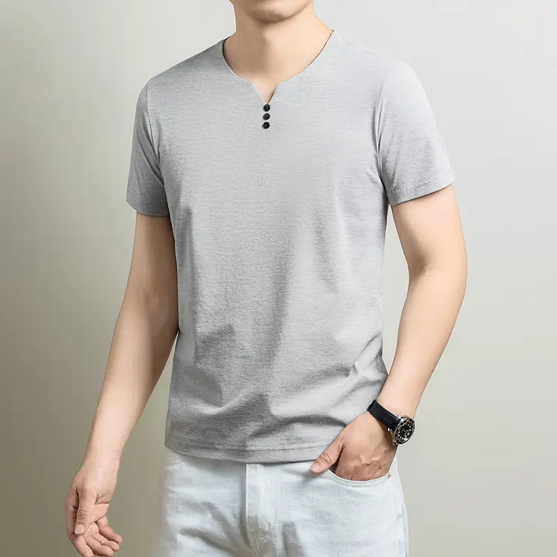 Una camisa henley informal para hombre de manga corta color gris claro, con tejido con textura, escote en V y tres botones negros en el cuello.