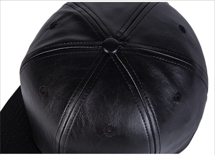 Gorra tipo snapback de cuero negro con visera plana, que presenta paneles cosidos y un botón central.