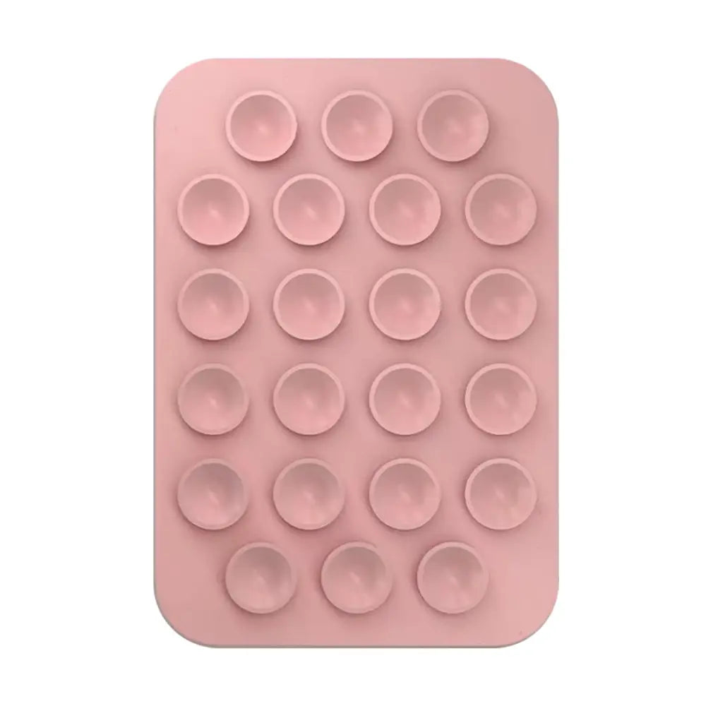 Un tapis de jeu anti-stress pop-it en silicone rose avec 25 indentations circulaires, présenté à côté d’un support de téléphone magnétique à ventouse pour iPhone Pro Max.