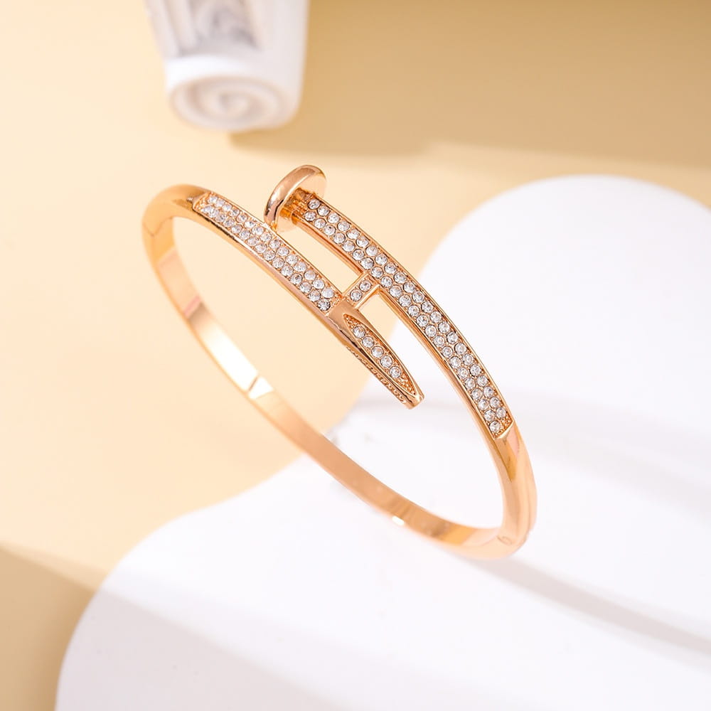 Bracelet jonc en zirconium cubique intersectant à tons dorés, orné d’une rangée de strass transparents étincelants le long de sa longueur.