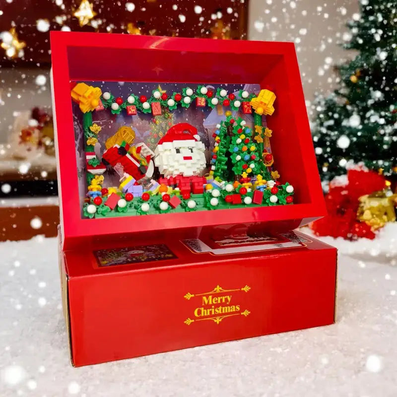 Caja tipo diorama Lego roja de Navidad que presenta una figura de Papá Noel rodeada de adornos de vegetación festiva y regalos para el juguete de bloques de construcción de vacaciones de Christmas TV.