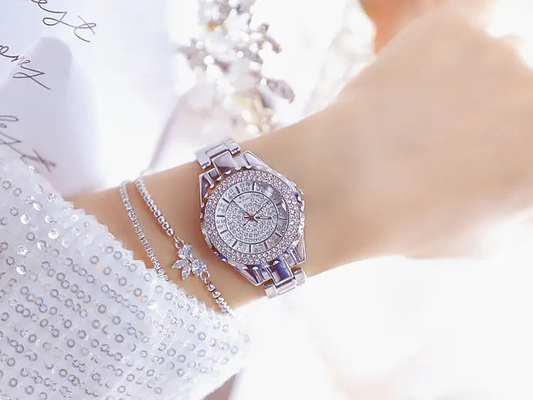 きらめくシルバーのゴールドダイヤモンド婦人用ドレスウォッチ。ダイヤモンドで敷き詰められた文字盤とバンドを備え、手首に着用し、繊細なブレスレットを合わせて着用します。