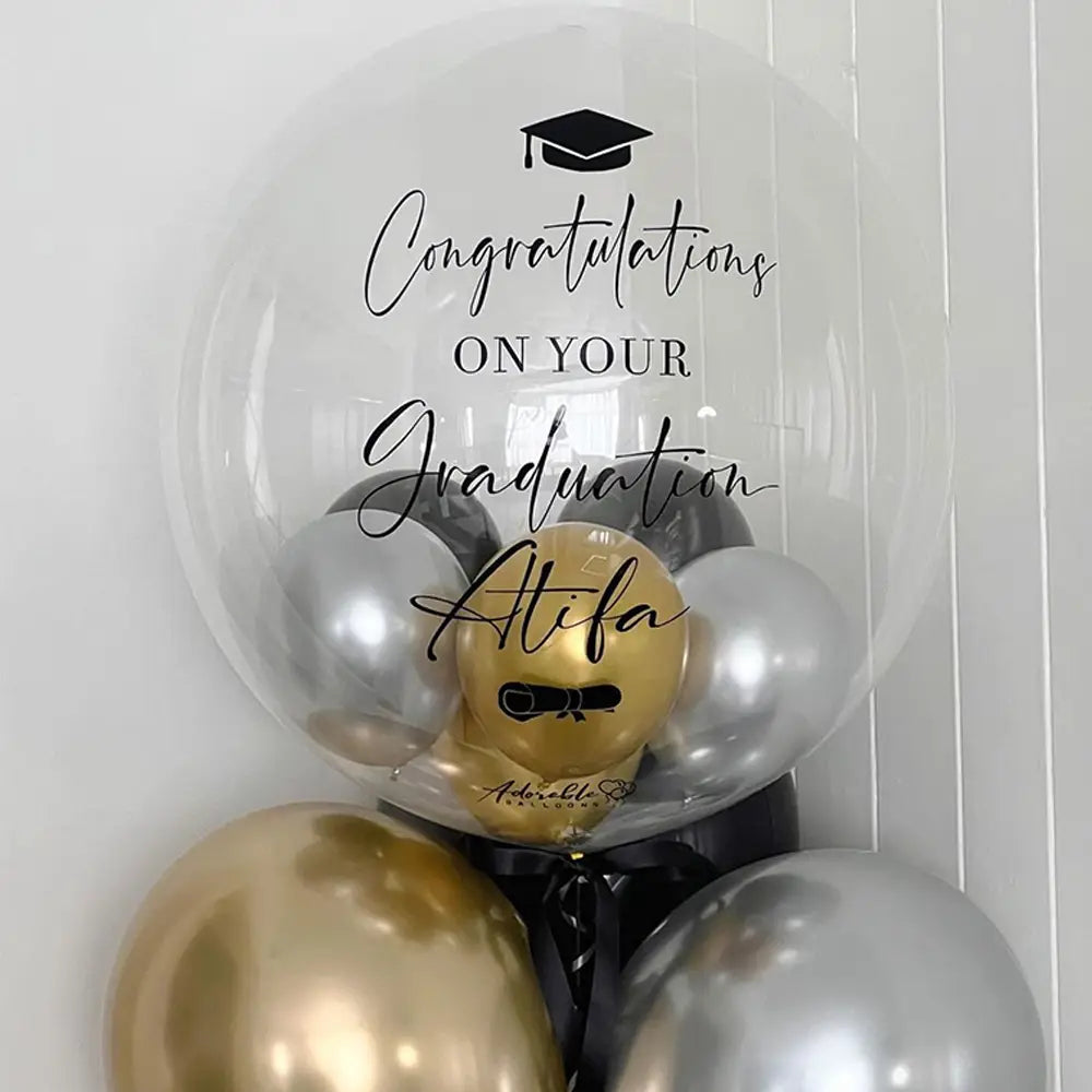 Individueller Baby-Party-Ballonaufkleber mit schwarzer geschwungener Schrift „Congratulations“ zur Graduation, Atifa-Text und Symbol einer Graduation-Mütze auf einem transparenten 36-Zoll-Bobo-Ballon, der kleinere goldene und silberne Ballons im Inneren enthält