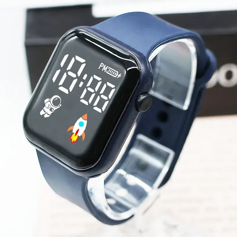 Montre électronique bleu marine pour enfants, garçons et filles, avec un cadran carré et un graphisme d’astronaute et de fusée sur l’affichage numérique LED de type sport.