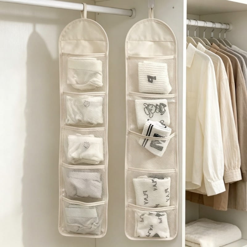 Beiger hängender Kleiderschrank-Organizer aus Stoff mit fünf Mesh-Taschen, in denen jeweils ordentlich gefaltete Socken zur Aufbewahrung verstaut sind.