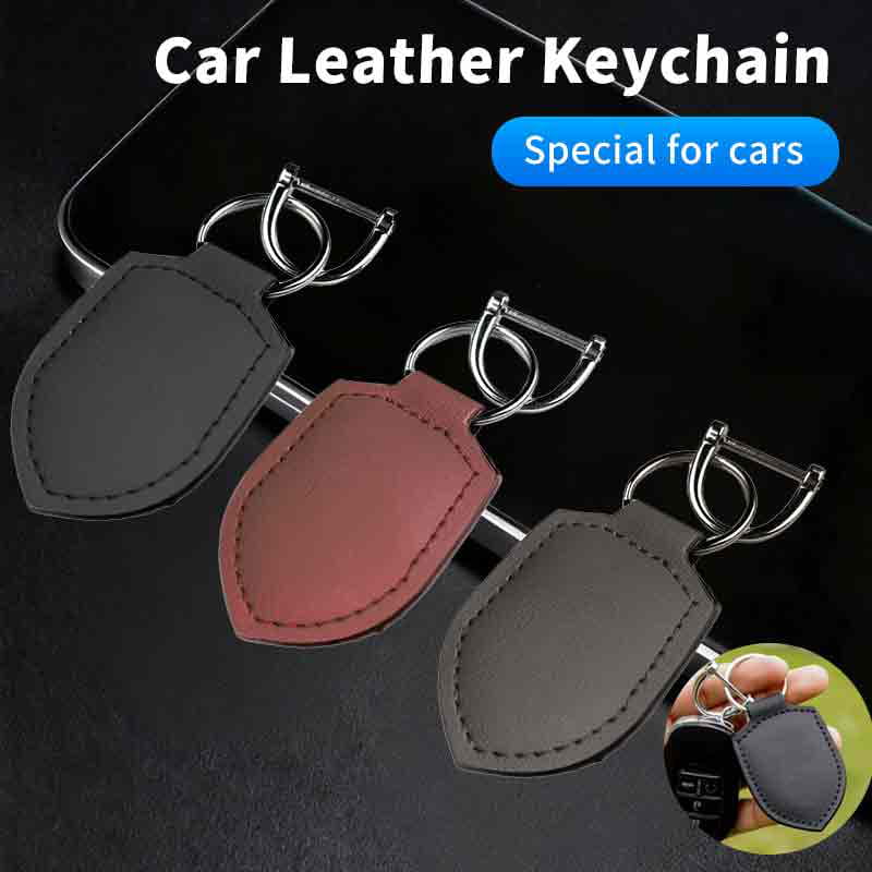Three shield-shaped leather car keychain ring organizers in black, reddish-brown, and dark gray with stitched edges and silver metal rings.