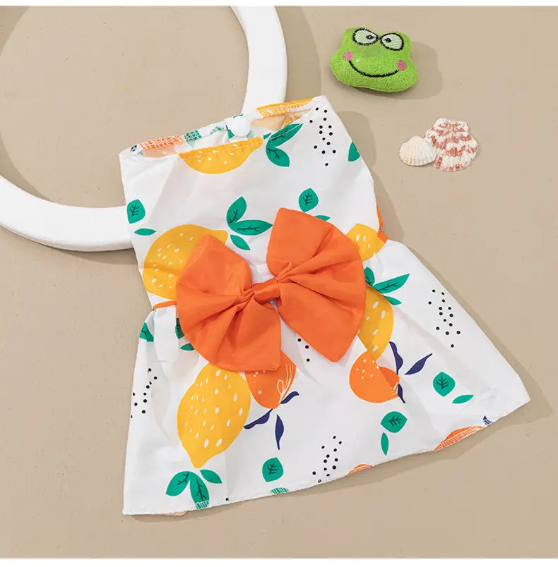 Floral dog princess dress with bow featuring a white fabric with a vibrant citrus print and an oversized orange bow at the waist.