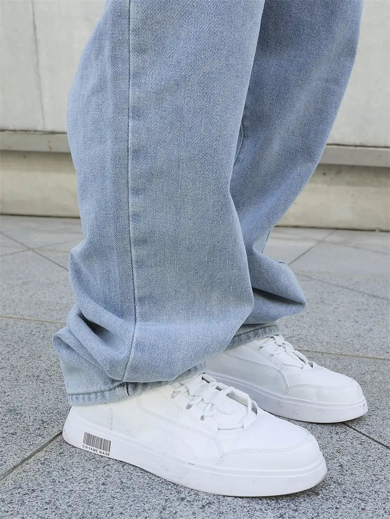 Baskets basses blanches à la conception minimaliste et épurée, avec un marquage discret au niveau du talon, associées à un jean en denim Y2K hommes ample à jambe large.