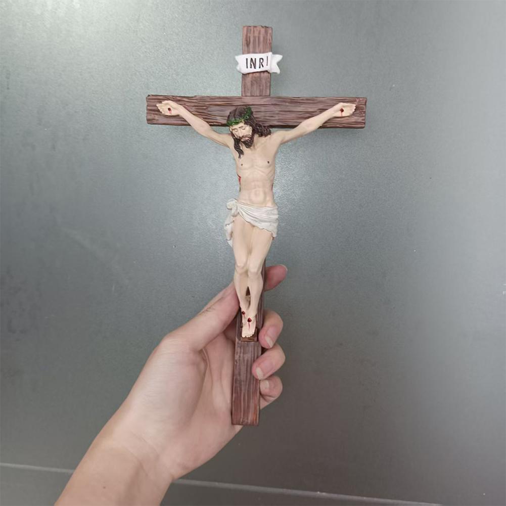 Figura de cruz pascual de resina detallada, con una figura de Jesús de cabello y barba largos y oscuros, vestido con una tela blanca alrededor de la cintura, montada sobre una cruz de madera coronada por un estandarte de INRI para decoración religiosa del hogar.