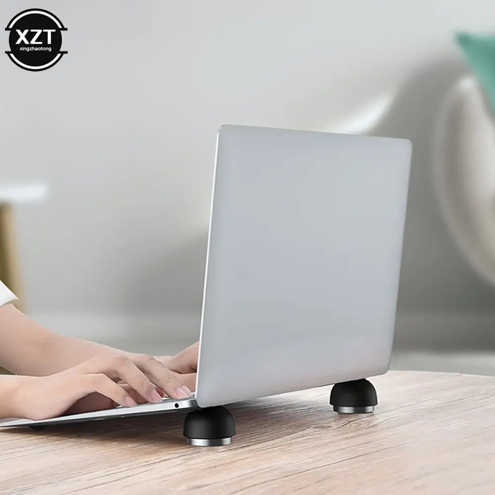 Silbernes Laptop, erhöht durch zwei schwarze kreisförmige Magnetständer eines klappbaren Mini-Laptop-Ständer-Kühlerhalters.