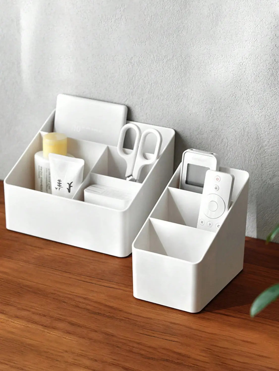 White plastic desk organizer and remote holder with multiple compartments holding various small items.