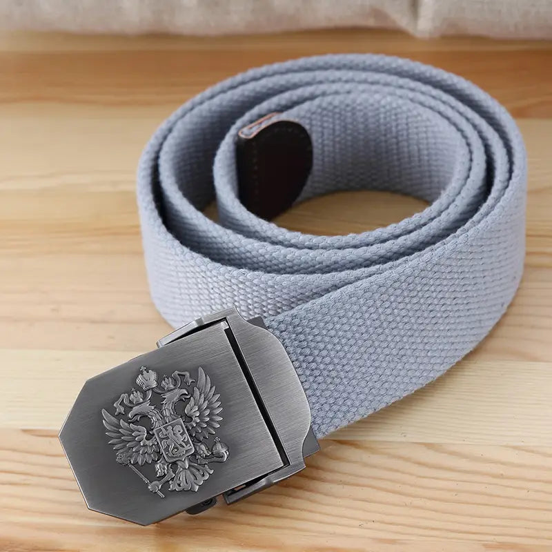 Ceinture tactique en toile grise pour hommes, avec une boucle argent métallisé présentant un emblème d’aigle bicéphale gravé, conçu pour un usage militaire.