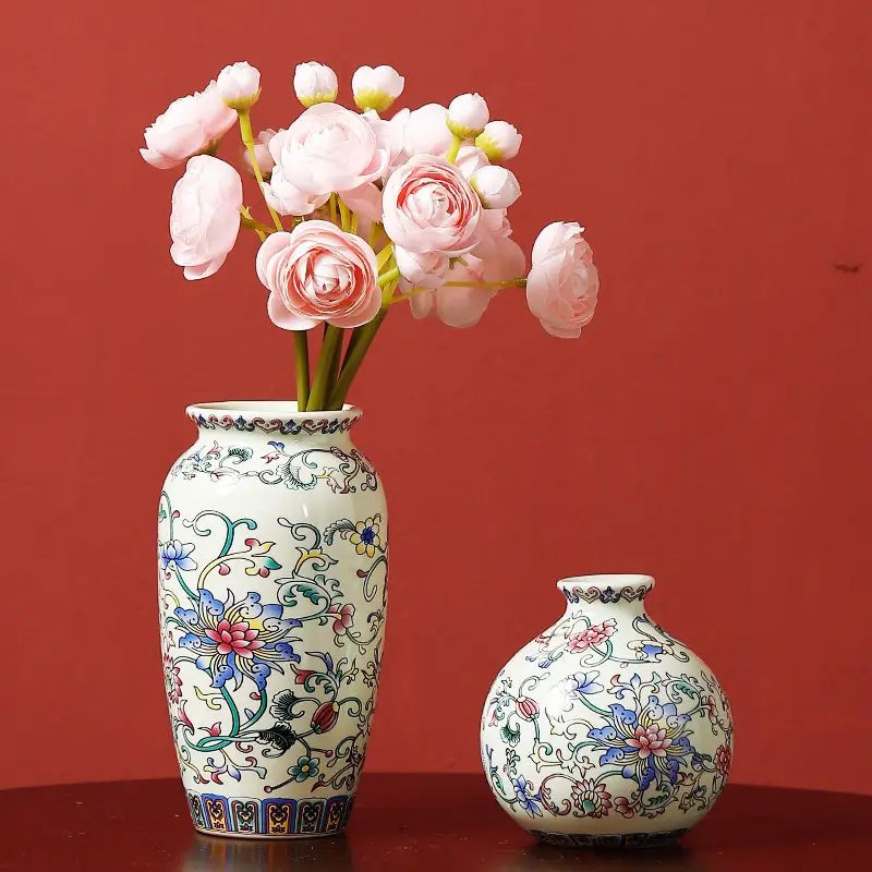 Un petit vase en émail de céramique blanc, présentant des motifs floraux bleus-verts et roses complexes, dans un style de porcelaine chinoise d’inspiration ancienne.