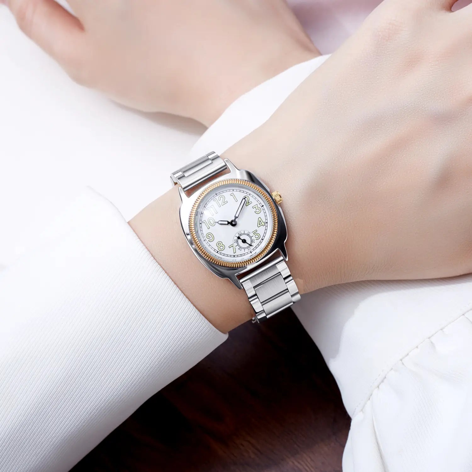 A sleek silver and gold tone pintime stainless steel quartz watch for women with a white dial black arabic numerals and a polished metal bracelet.