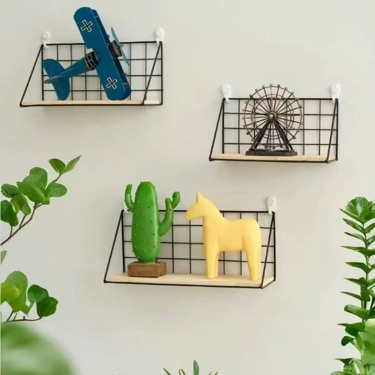 Wood wall shelf with black wire basket storage and light wood base holding decorative items on a grid wall.