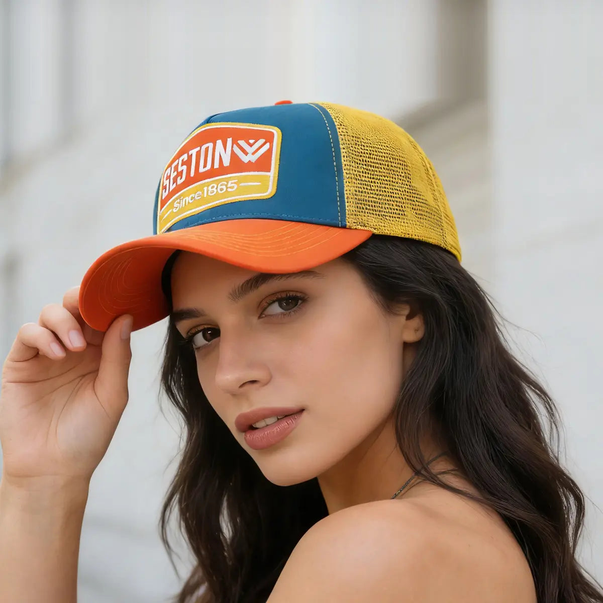 Vibrant orange blue and yellow trucker hat with a seston logo patch reading geston since 1865 on the front.