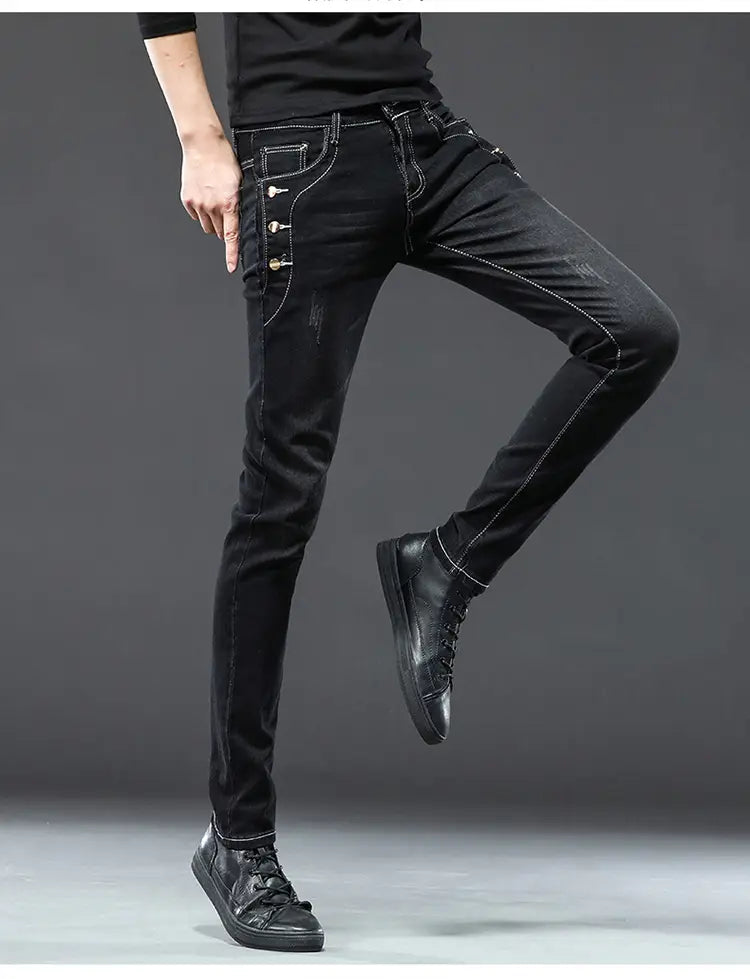 Jeans slim en denim extensible vintage pour hommes, lavage gris, avec coupe skinny noire, surpiqûres blanches et boutons dorés décoratifs sur la couture latérale.