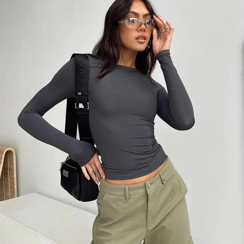 Blusa corta ajustada tipo slim fit negra de manga larga y fruncida para mujer, confeccionada con tejido elástico suave, ideal para un uso casual y con estilo.