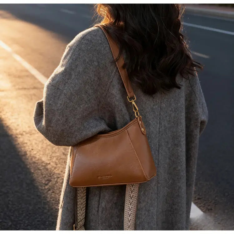 編み込みストラップとゴールドトーンの金具を備えた、タンレザー素材の女性用ブラウンレザーのクロスボディショルダーバッグ。