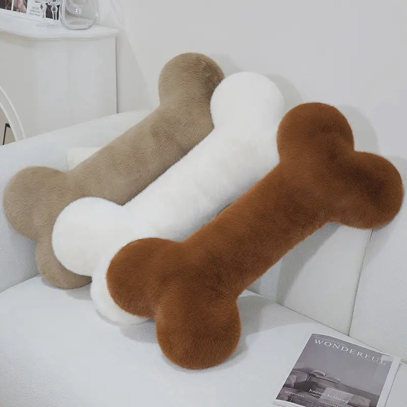 Three kawaii bone shape plush pillows in beige white and brown fur designed as soft nap cushions.