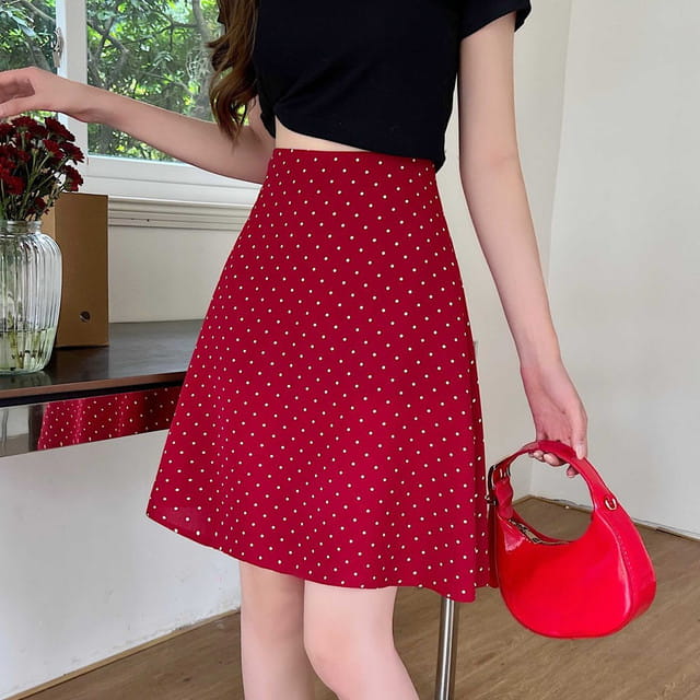 Falda midi línea A roja con lunares blancos que presenta lunares blancos y un bajo acampanado, adecuada para uso informal y semiformal.