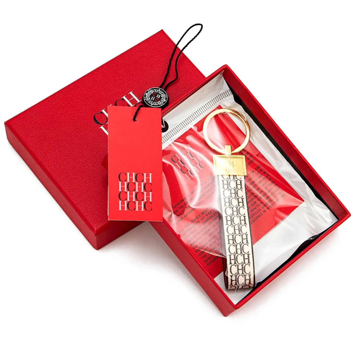 A sleek gold-toned leather logo keychain with a black and white repeating chch monogram strap displayed in an elegant red gift box.