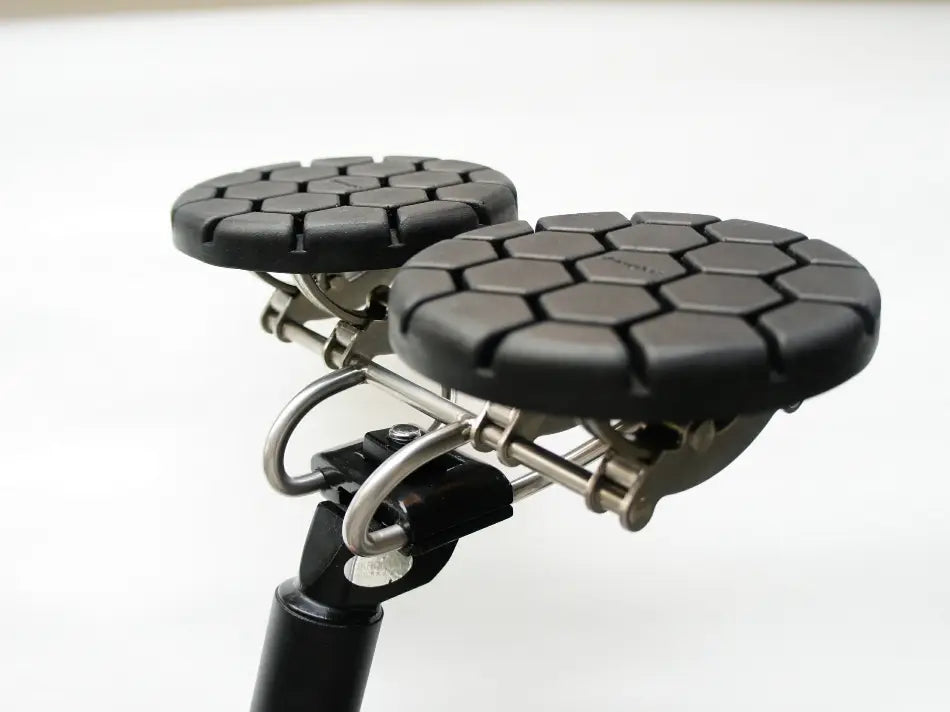 Nasenloser ergonomischer Fahrradsattel für lange Strecken mit schwarzem sechseckigem Muster und metallischem Rahmen, von der Rückseite dargestellt.