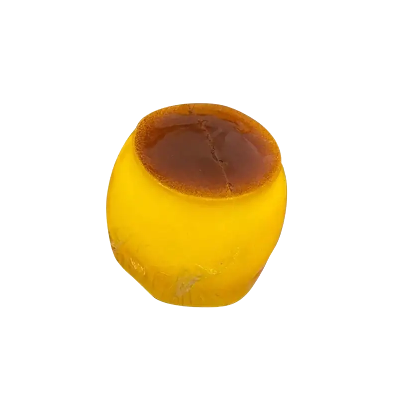 A front view of a golden-yellow translucent caramel pudding stress ball with a glossy brown top for stress relief