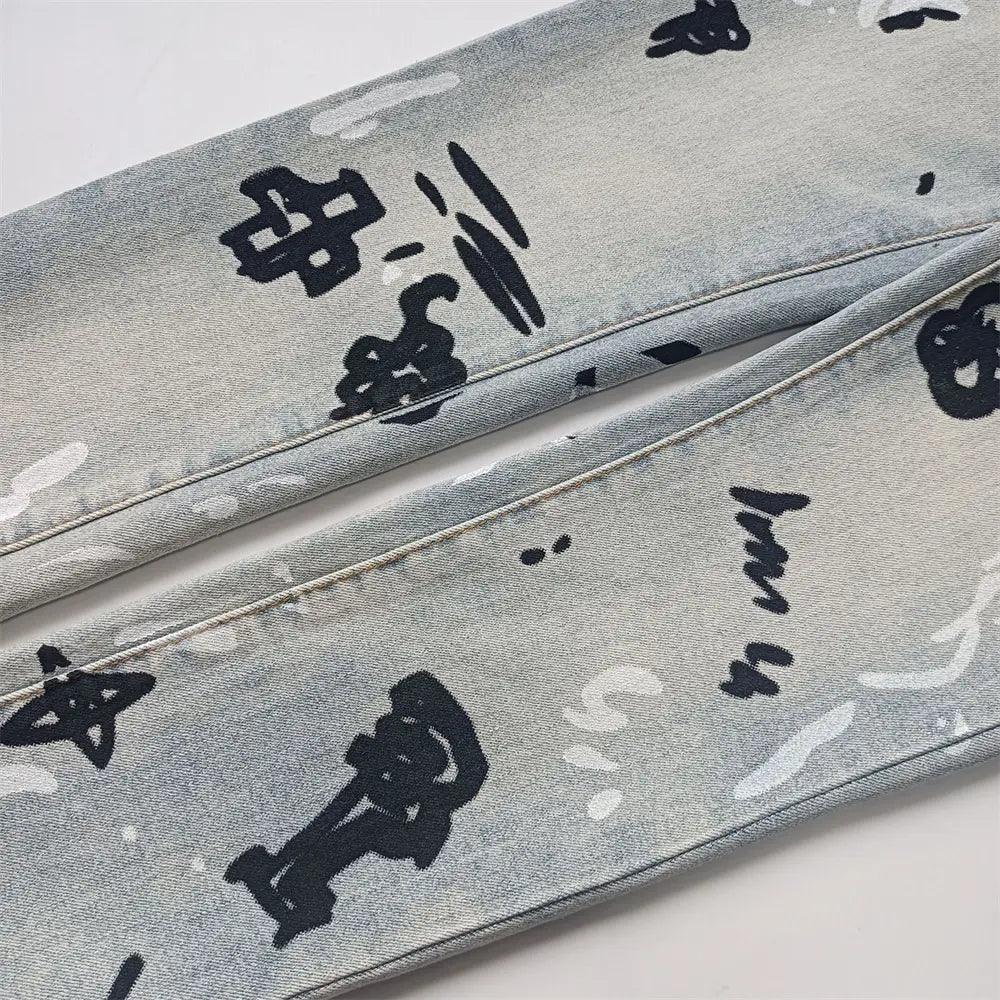 Jeans skinny déchirés pour hommes en denim à lavage clair, avec une grande impression graphique de type graffiti noir, et un délavage rétro vintage en bleu.