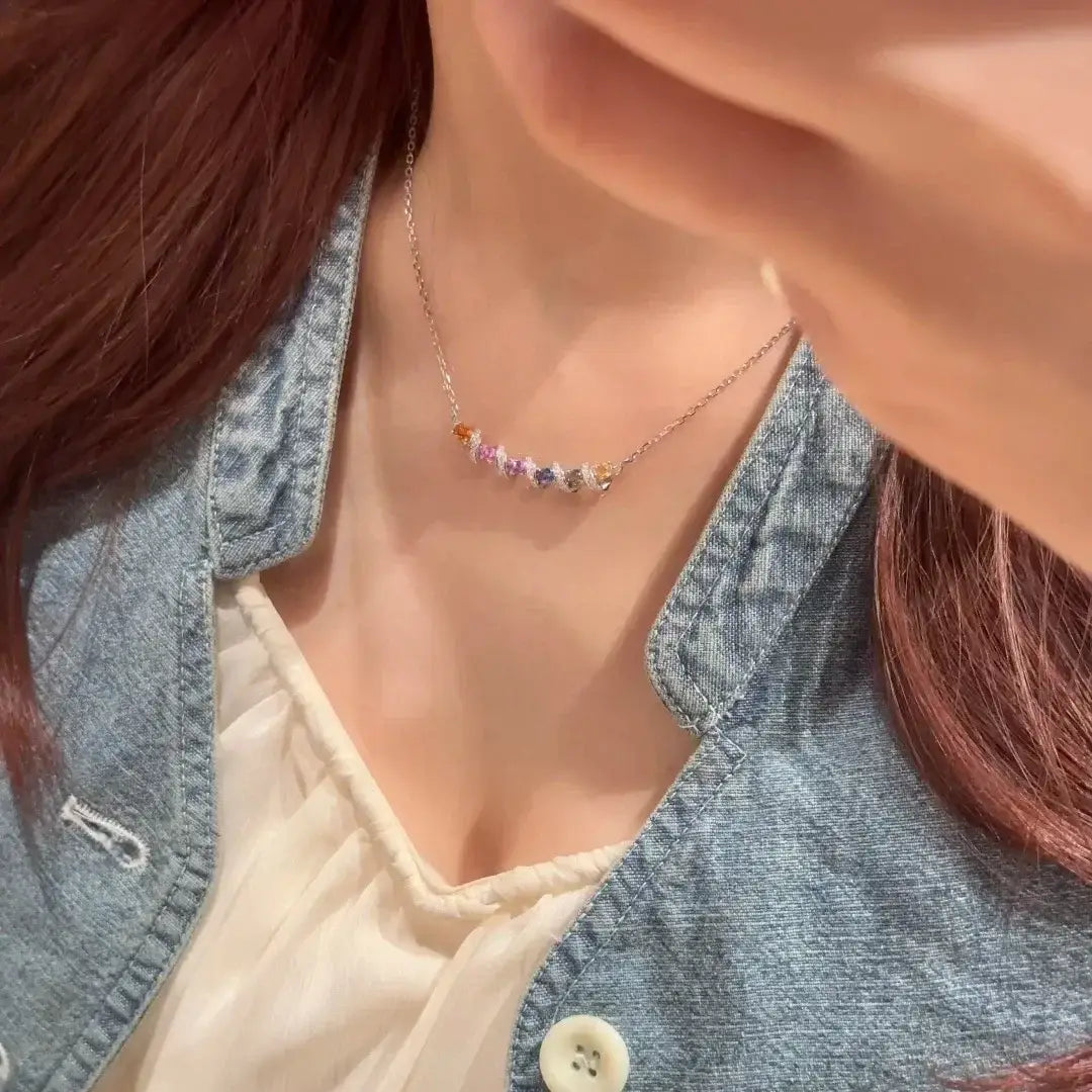 Un délicat collier en argent, avec un pendentif géométrique multigemme orné de pierres précieuses facettées colorées, sur une chaîne en or.