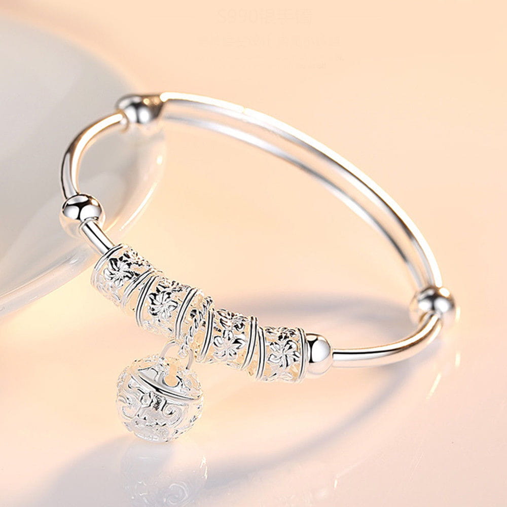 Bracelet jonc à billes grelots en argent sterling, avec un jonc en argent présentant une gravure florale détaillée sur des perles cylindriques et une breloque sphérique assortie, richement détaillée.