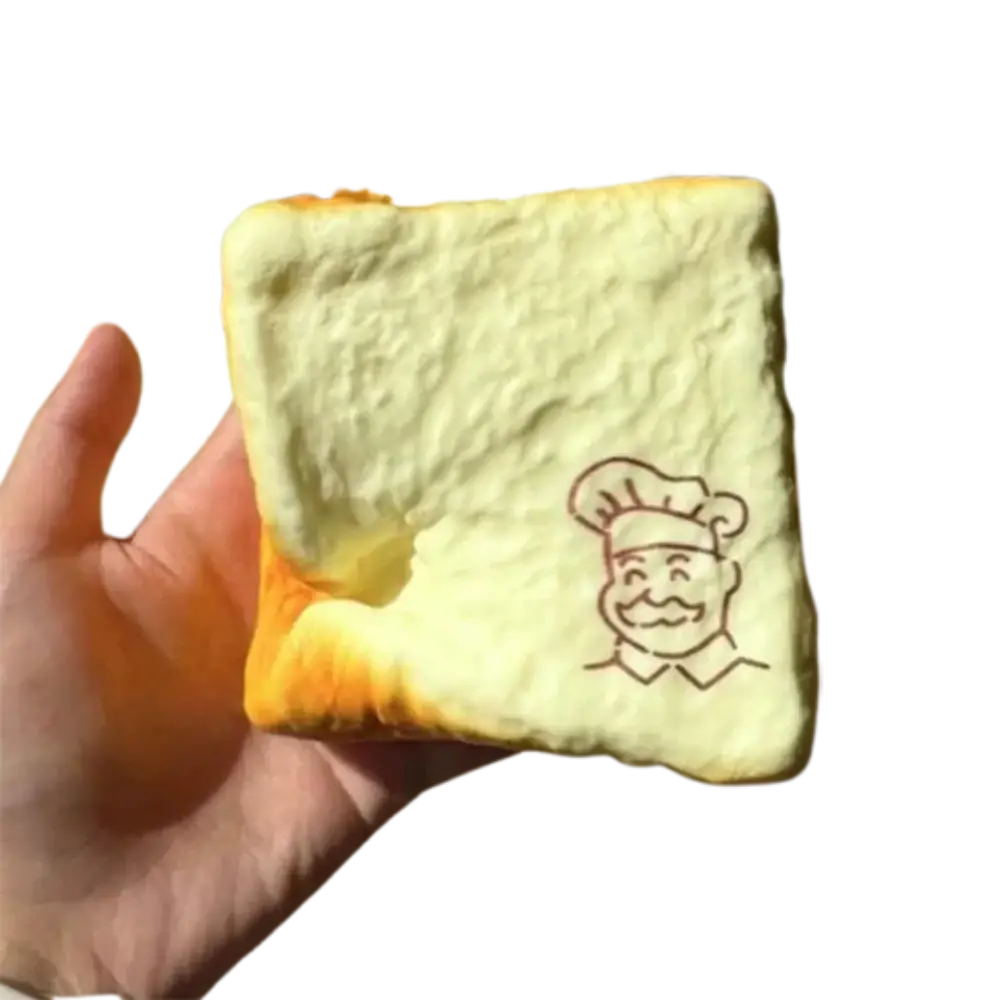 A soft pale yellow foam grandpa toast squishy toy with cartoon chef face designed as a fidget toy for universal age range