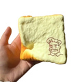 A soft pale yellow foam grandpa toast squishy toy with cartoon chef face designed as a fidget toy for universal age range