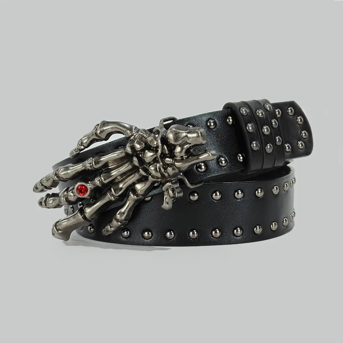 cinturón de cintura negro con tachuelas de cuero sintético tipo pu en estilo y2k con una hebilla detallada de mano de esqueleto en plata con una piedra preciosa roja en el dedo índice, en un estilo y2k de cruz bohemia