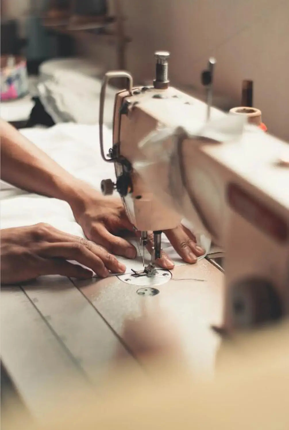 Una máquina de coser industrial de estilo vintage, con cuerpo metálico y acentos negros, cosiendo el juego completo de fundas universales para asiento de automóvil en negro y color canela.
