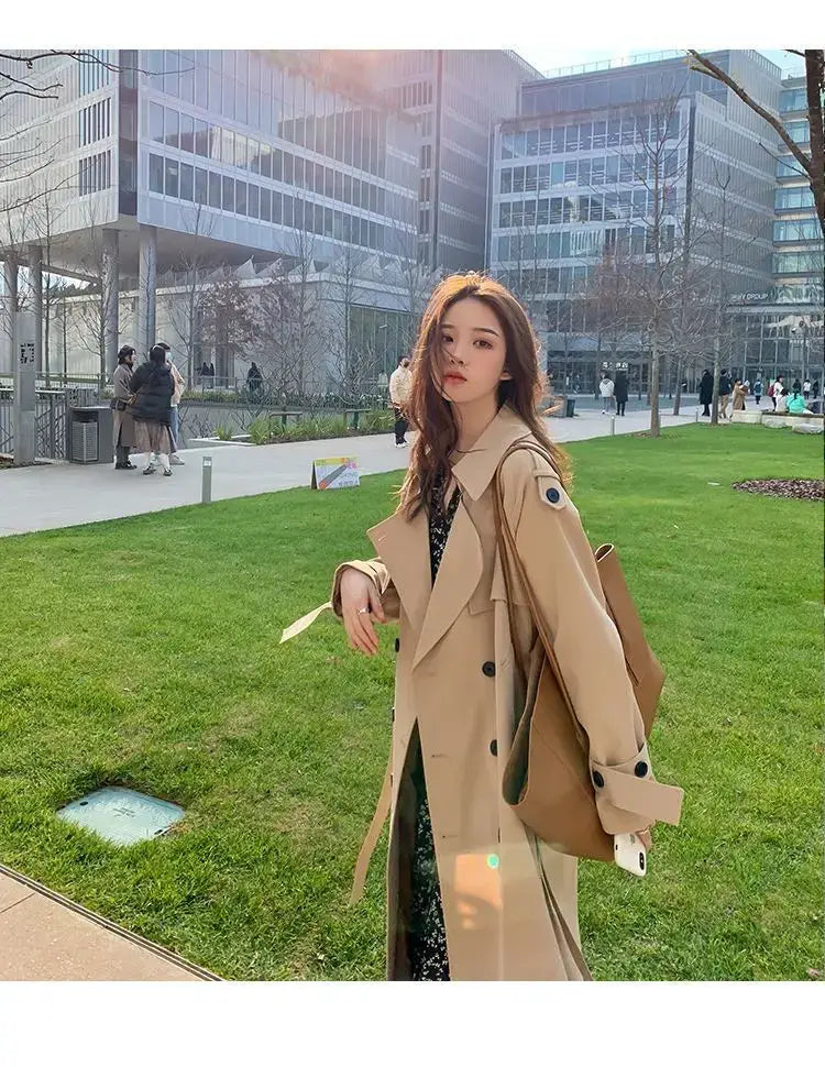 Beige double-breasted trench coat with black buttons and structured shoulder design for casual windbreaker use.