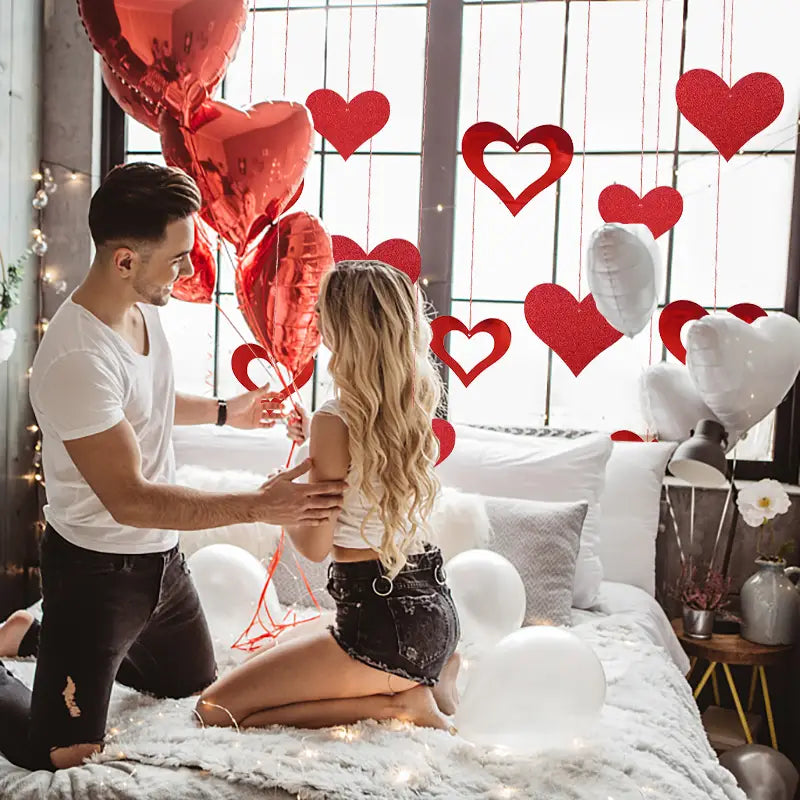 Globos rojos metálicos con forma de corazón incluidos en una guirnalda de corazones para San Valentín para decoración festiva.