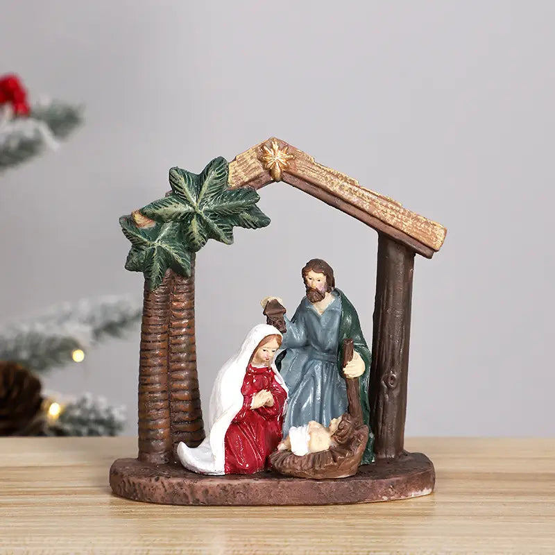 クリスマステーブルの装飾用に、赤いドレスと白いベールを着たマリア、青い衣をまとったヨセフ、そして木製のアーチ状の構造の下で緑のヤシの葉が飾られた飼い葉おけの中の幼子イエスを描いた、詳細な樹脂製の降誕飾りセット。