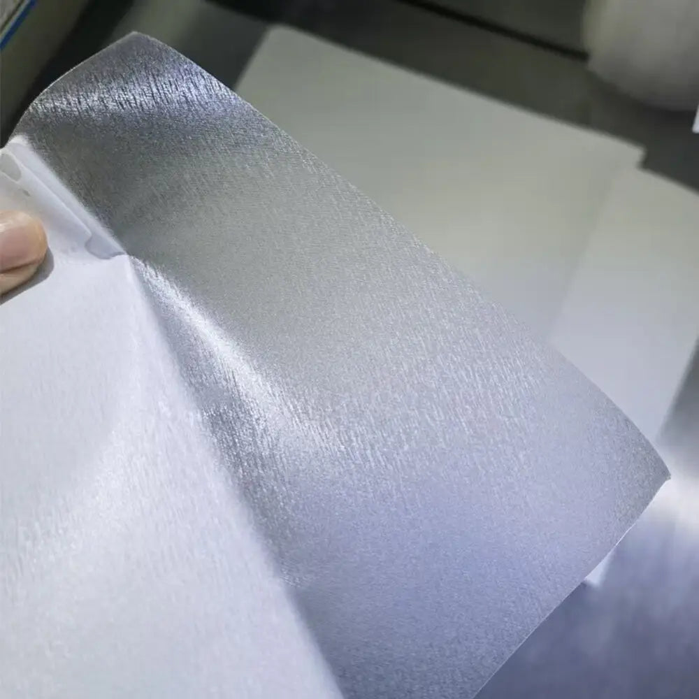 Lámina de metal plateada con acabado cepillado texturizado, utilizada en una máquina de laminación al vacío de película para teléfonos móviles para reducir el costo de envío y garantizar la calidad de la protección del teléfono móvil.