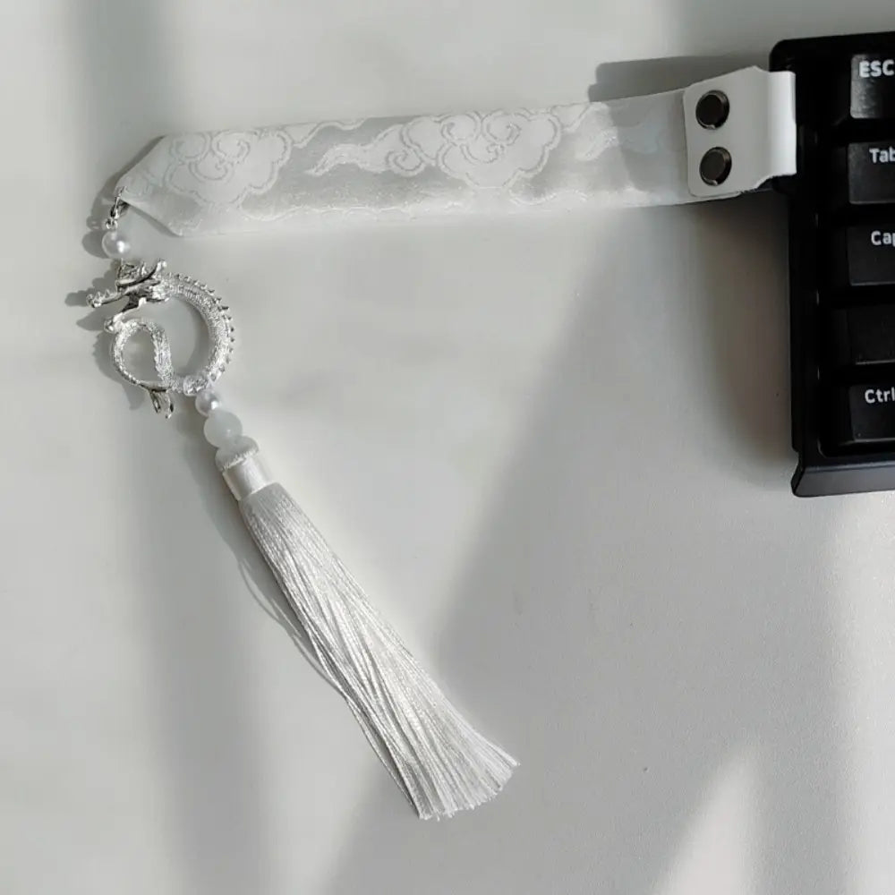 Marque-page en ruban de soie blanc avec breloque de dragon argentée et pompon, conçu comme une sangle personnalisée pour le clavier Wooting.