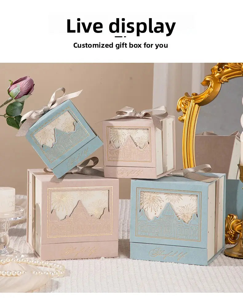 pastel blue and beige square european style wedding gift boxes with gold foil mountain landscape cutouts tied with satin ribbons for candy packaging