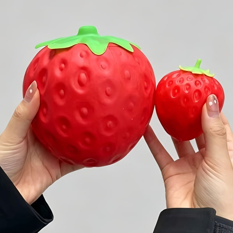 Jumbo strawberry slow rising sensory fidget toy shaped as a red strawberry with a textured surface and green leafy top designed as a stress ball.